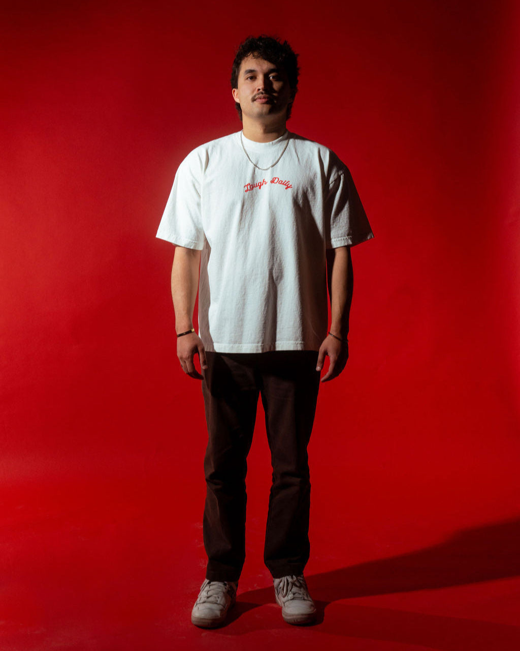 laugh daily apparel christian tee worn by model standing with red back drop